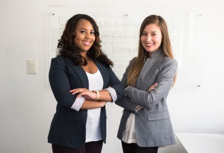 Women Entrepreneurs - two women in suits standing beside wall