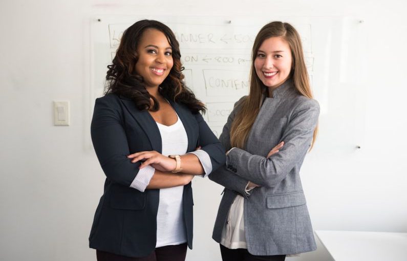Women Entrepreneurs - two women in suits standing beside wall