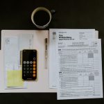 Tax - black Android smartphone near ballpoint pen, tax withholding certificate on top of white folder