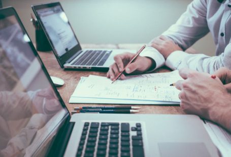 Startups Finance - person holding pencil near laptop computer