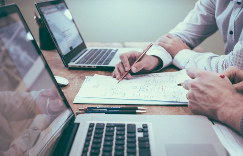 Startups Finance - person holding pencil near laptop computer