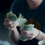 Consumers - focus photography of person counting dollar banknotes