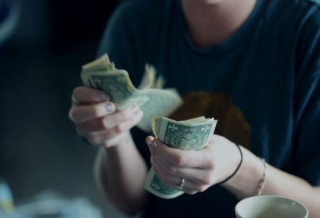 Consumers - focus photography of person counting dollar banknotes