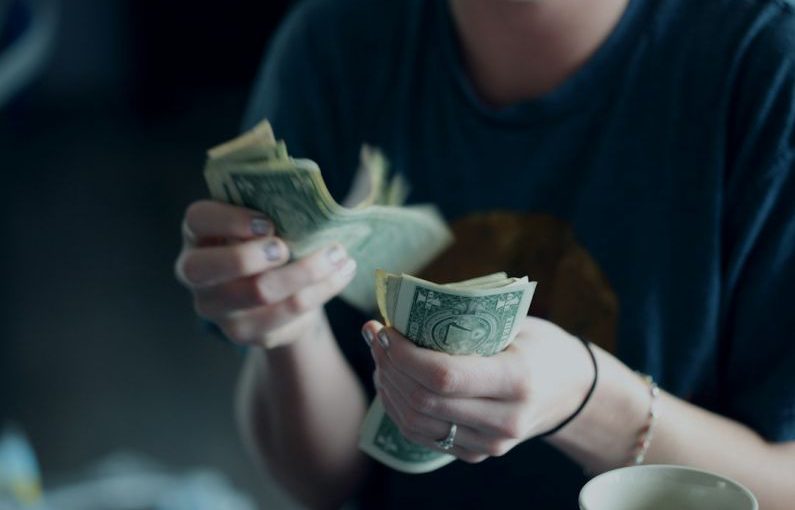 Consumers - focus photography of person counting dollar banknotes