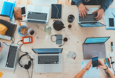 E-commerce - people sitting down near table with assorted laptop computers