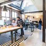 Startups - man standing beside another sitting man using computer