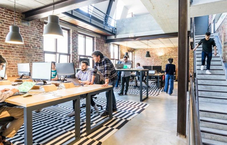 Startups - man standing beside another sitting man using computer