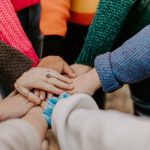 Team - person in red sweater holding babys hand