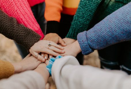 Team - person in red sweater holding babys hand