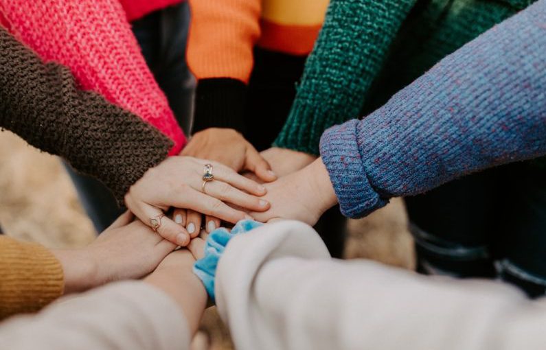 Team - person in red sweater holding babys hand