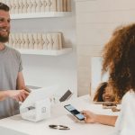 Customer - man in grey crew-neck t-shirt smiling to woman on counter