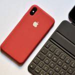 Technological - space gray iPhone with red case beside tablet keyboard