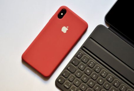 Technological - space gray iPhone with red case beside tablet keyboard