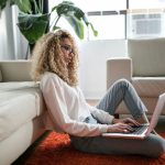 Fitness Laptop - woman sitting on floor and leaning on couch using laptop