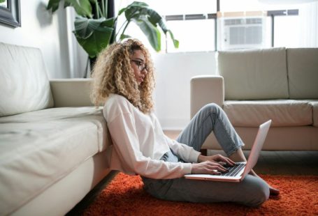 Fitness Laptop - woman sitting on floor and leaning on couch using laptop