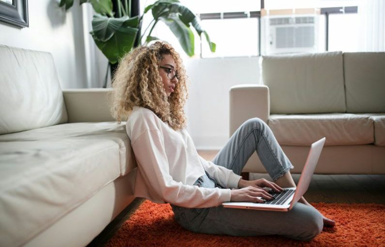 Fitness Laptop - woman sitting on floor and leaning on couch using laptop