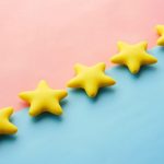 Reviews - a row of yellow stars sitting on top of a blue and pink surface