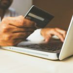 Online Marketplace - person using laptop computer holding card
