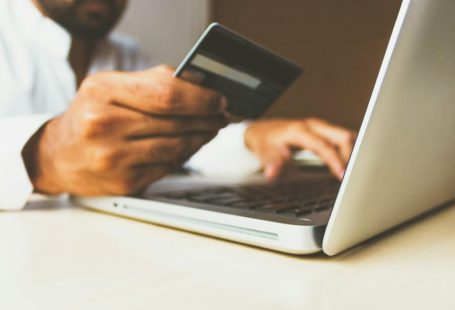 Online Marketplace - person using laptop computer holding card