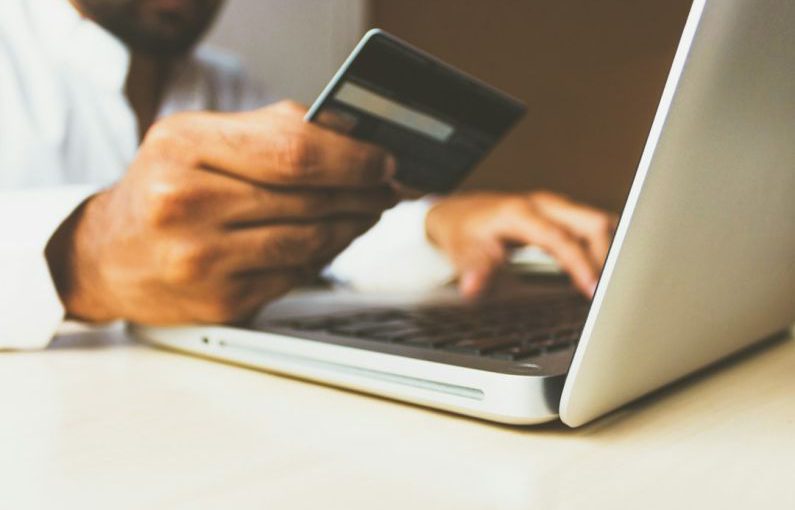 Online Marketplace - person using laptop computer holding card