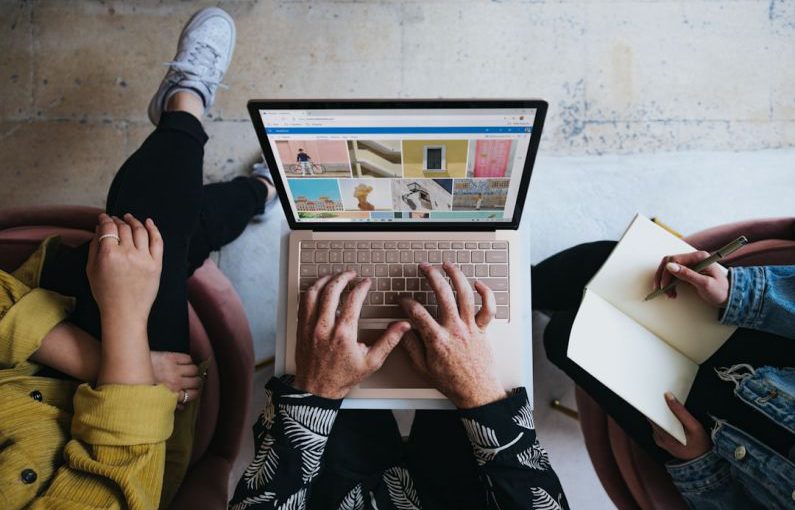 Marketing - person using microsoft surface laptop on lap with two other people