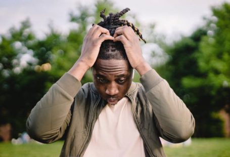 Startup Mistake - Upset young African American male freelancer clutching head with hands after failure in project while working remotely in park