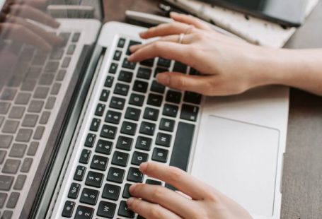 5G Network - From above of unrecognizable woman sitting at table and typing on keyboard of computer during remote work in modern workspace