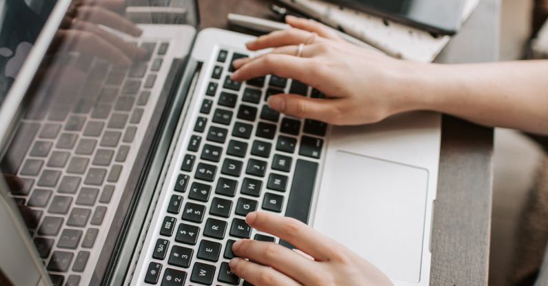 5G Network - From above of unrecognizable woman sitting at table and typing on keyboard of computer during remote work in modern workspace