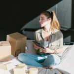 Ecommerce Startup - A Woman in Bed with Brown Boxes while Holding a Tablet