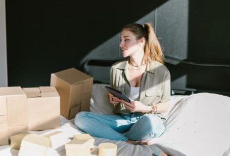 Ecommerce Startup - A Woman in Bed with Brown Boxes while Holding a Tablet