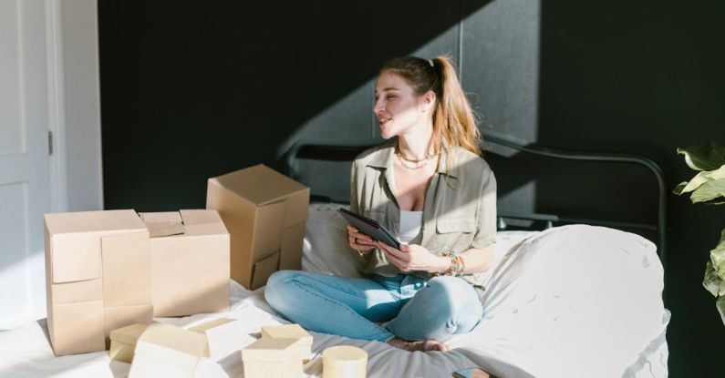 Ecommerce Startup - A Woman in Bed with Brown Boxes while Holding a Tablet