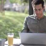 Smart City Startup - Focused black male freelancer using laptop in street cafe