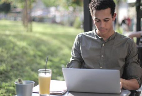Smart City Startup - Focused black male freelancer using laptop in street cafe