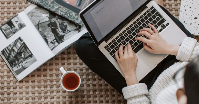 Education Startup - Crop young businesswoman using laptop while drinking tea at home