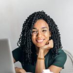 Remote Work Setup - Happy ethnic woman sitting at table with laptop