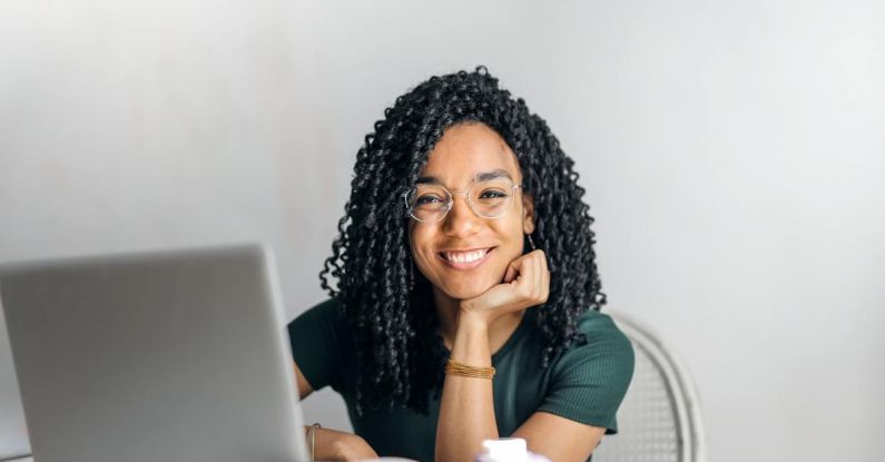 Remote Work Setup - Happy ethnic woman sitting at table with laptop